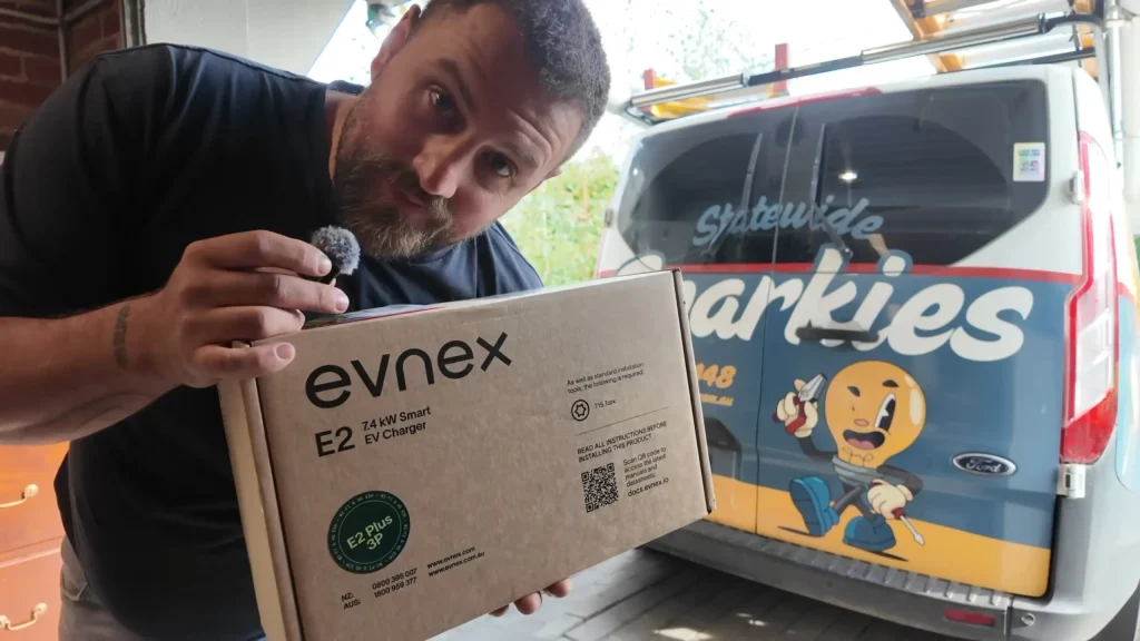 Jay Holding An Evnex EV Charger next to the Statewide Sparkies work Ute