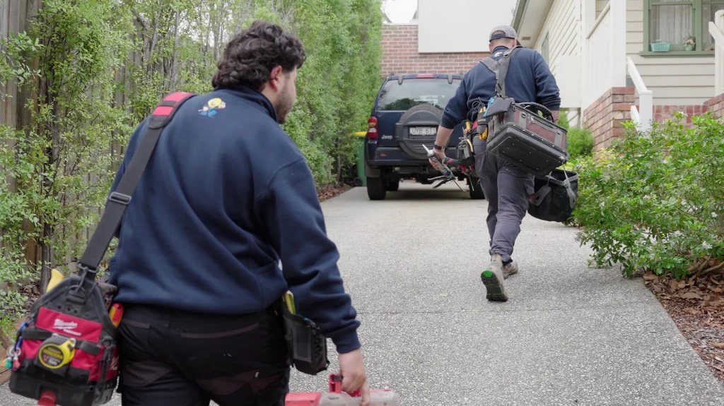Two Statewide Sparkies electricians carrying tool bags walking up to a residential property to begin an electrical job