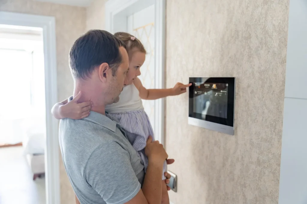 Family interacting with a wall-mounted home security control panel in a Melbourne residence