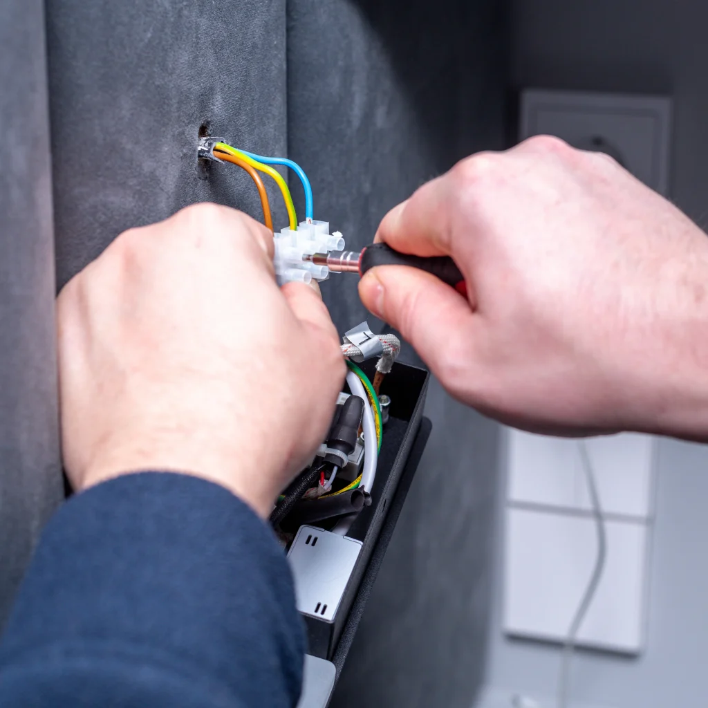 Electrician connecting electrical wiring into a wall fitting during a kitchen renovation