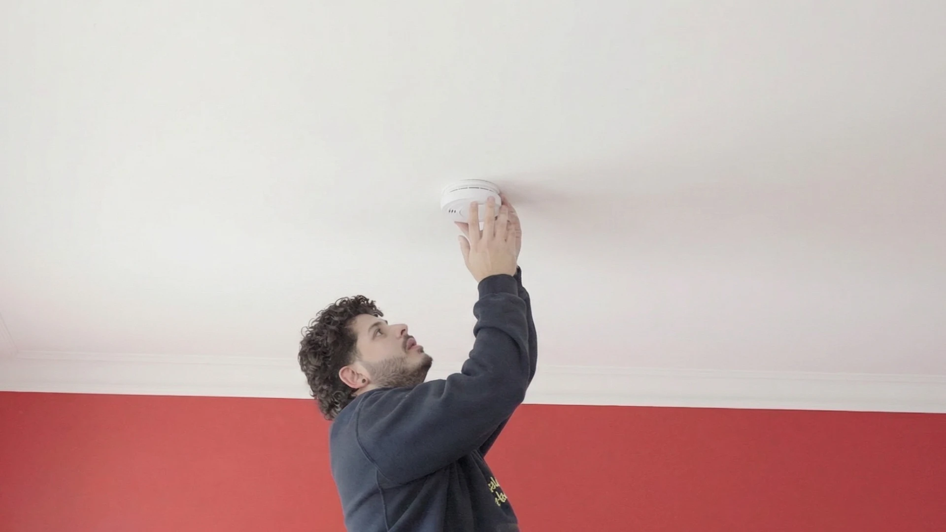 Statewide Sparkies electrician installing a smoke alarm on a residential ceiling