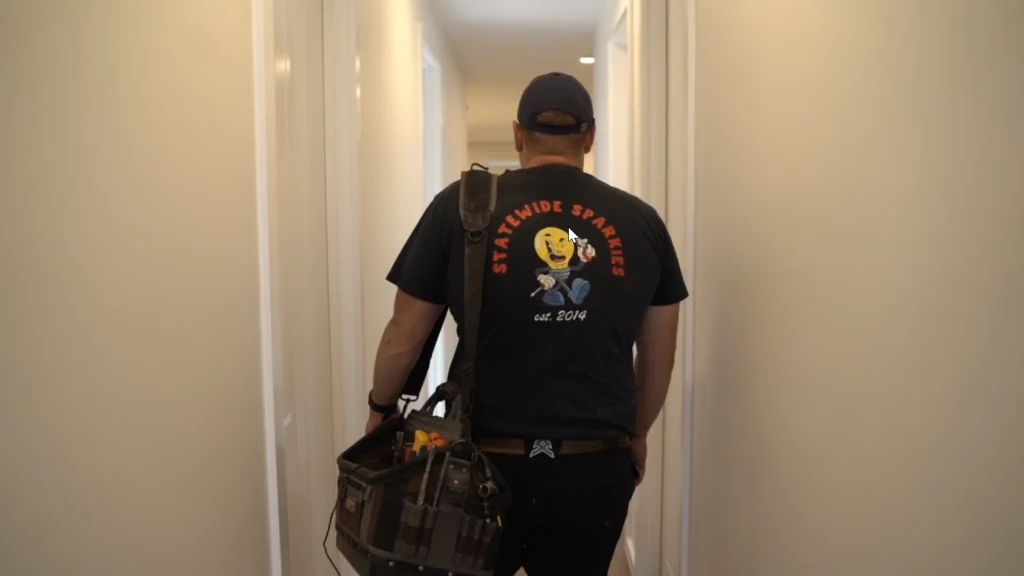 Statewide Sparkies electrician carrying a tool bag walking through a residential hallway on the way to a job