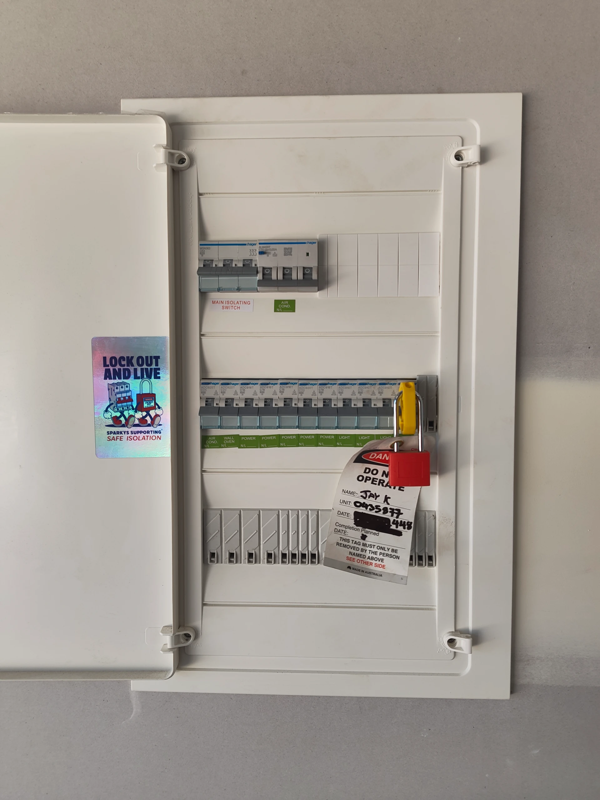 Residential switchboard with circuit breakers fitted with a safety lockout padlock and danger tag during safe isolation by a licensed electrician